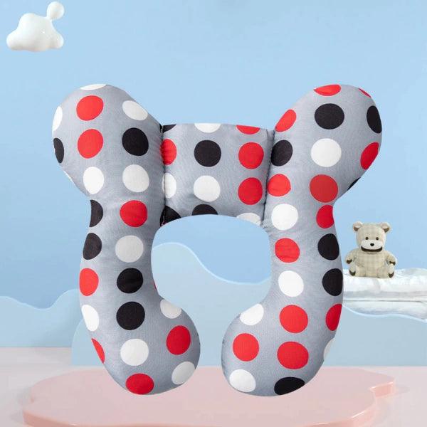 Almofada infantil ergonômica cinza com estampa de bolinhas vermelhas, pretas e brancas, fundo decorativo azul.